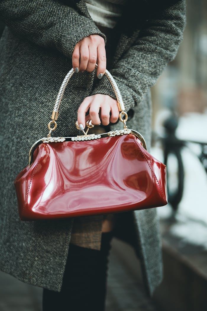 Mastering the First Impression: Your intriguing post title goes here A stylish woman holds a shiny red leather handbag outdoors, showcasing fashion elegance.